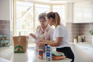 Photo of home care representative helping resident with groceries in kitchen