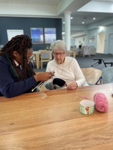 A student and retiree knitting together