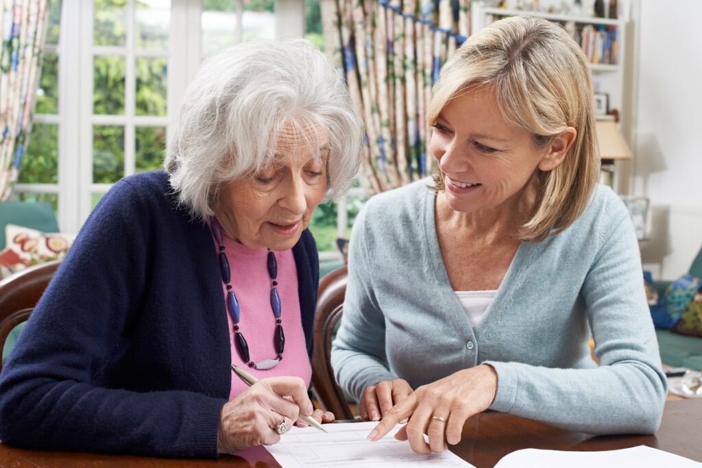 Older lady writing an advanced care directive with a younger lady