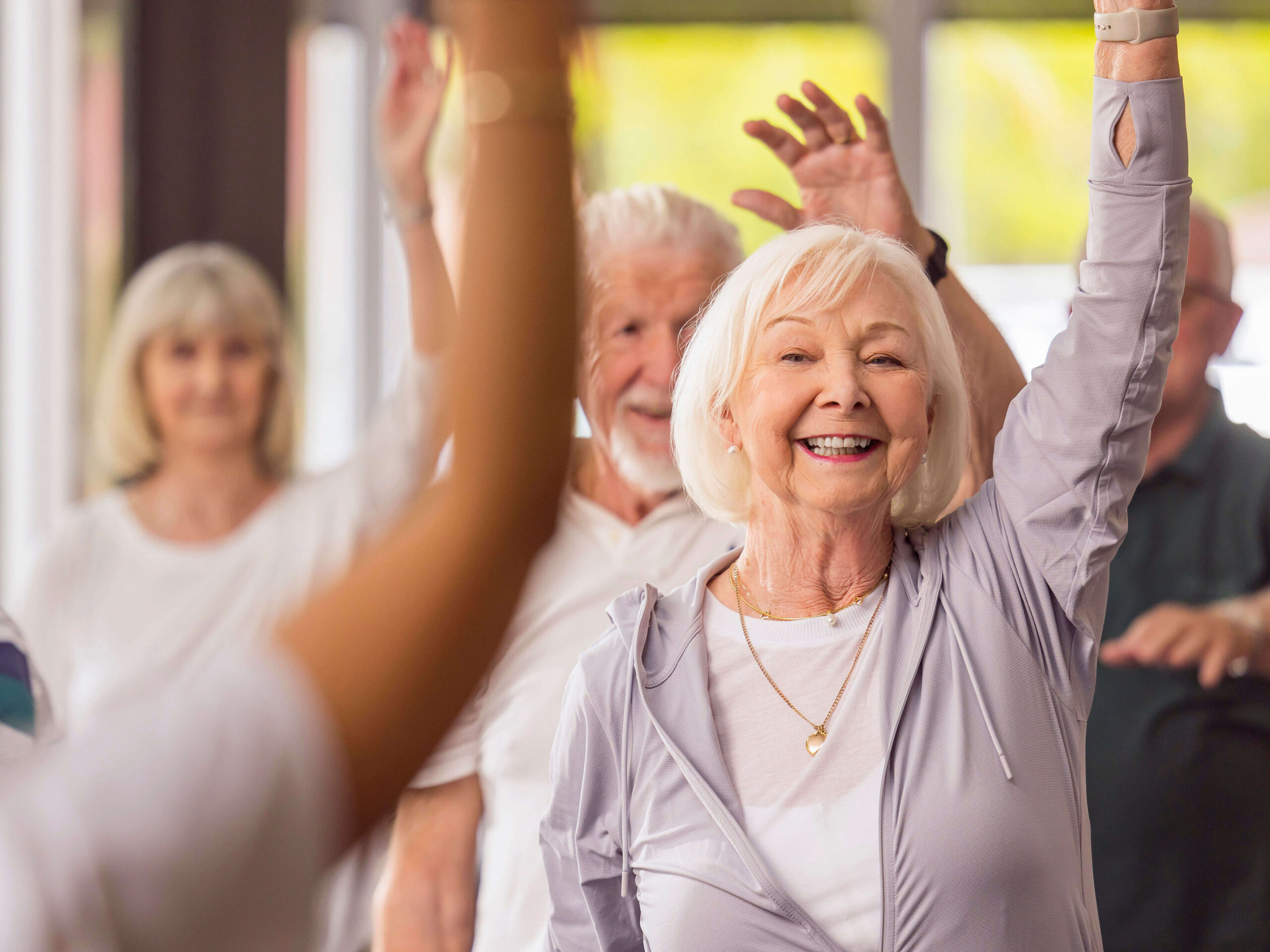 group of residents holding up their hands smiling