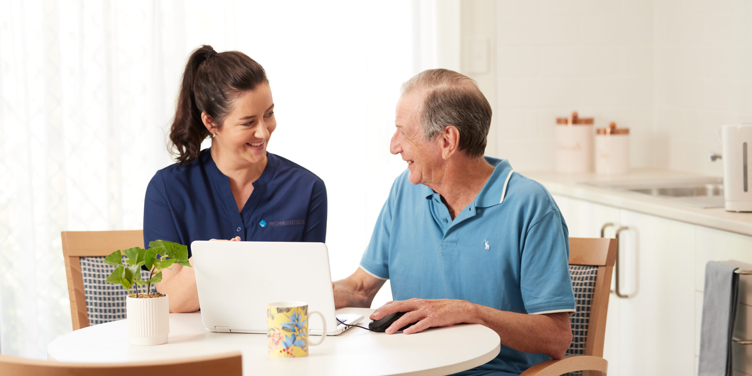 Nurse helping elderly man with laptop