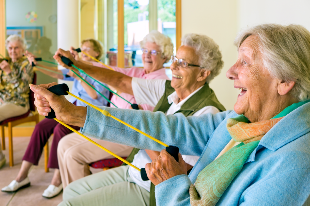 Group of older women doing chair exercises with resistance bands