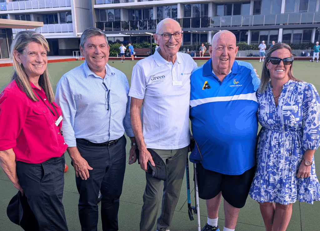 A group of village managers and residents standing together smiling at a bowling event